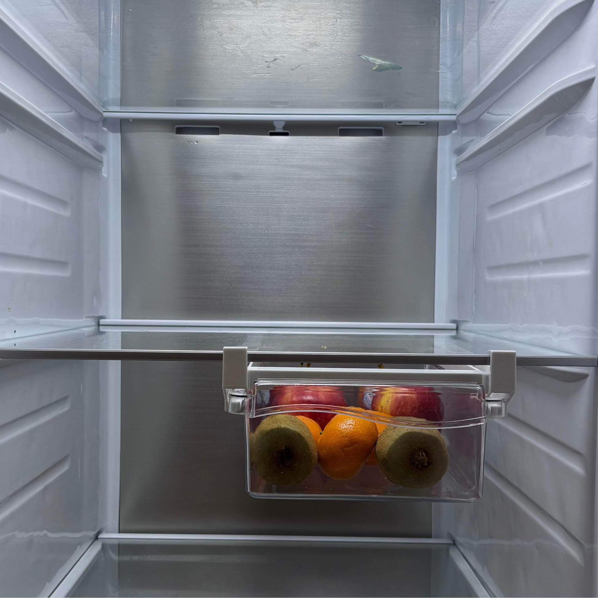 Small refrigerator with a clear door shelf containing fruits and vegetables.
